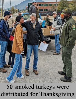 Group of volunteers unload turkeys from pickup captioned: "50 Smoked turkeys were distributed for Thanksgiving"